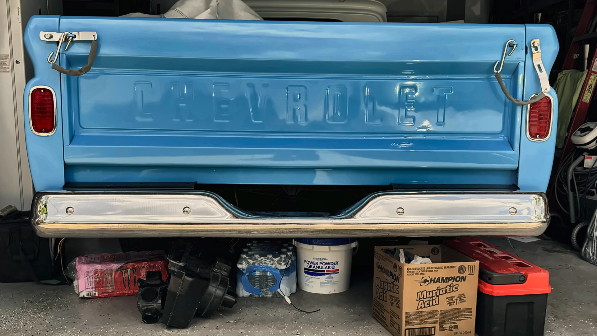 Black Chevrolet pickup with the tailgate down in the workshop, shop lights on the paint.